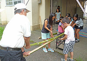 長い竹を協力して縦二つに割っています。